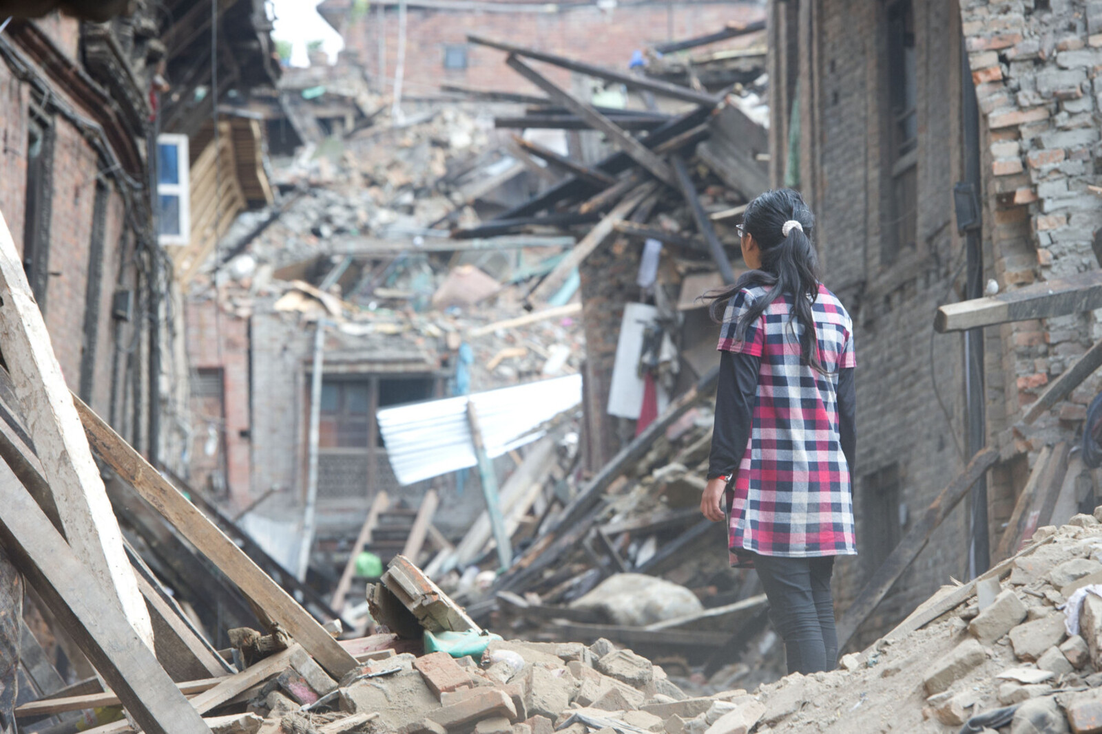 Eine Frau betrachtet in Bhaktapur, Nepal, ein von einem Erdbeben zerstörtes Haus