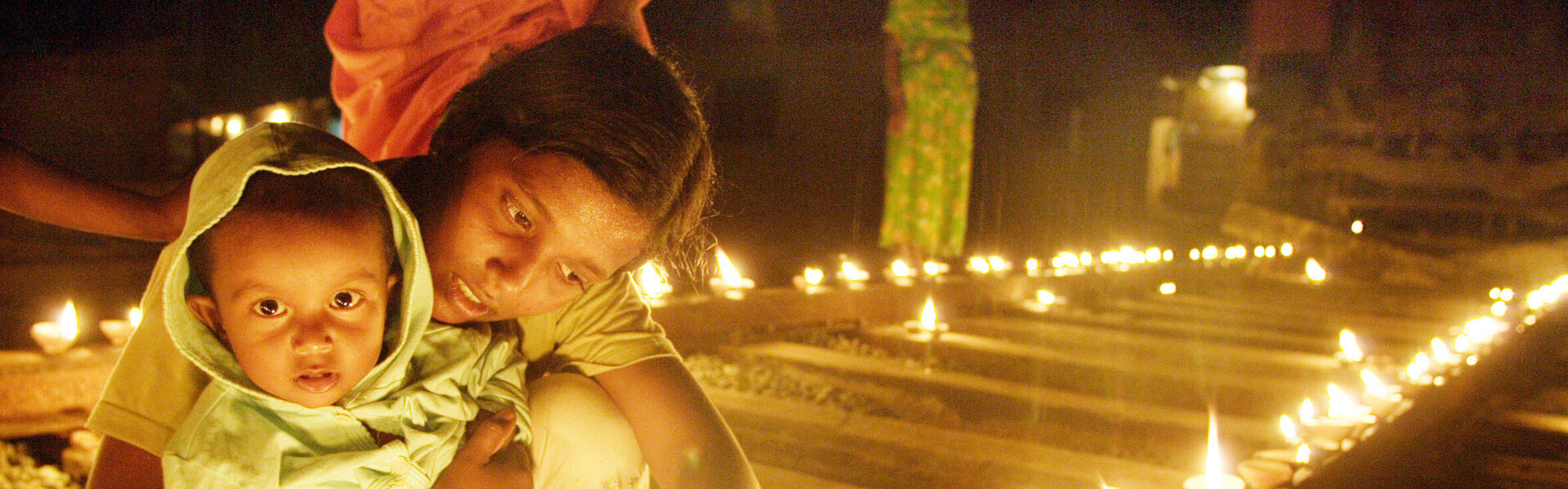 Eine Mutter zündet mit ihrem Kind eine Kerze zum Gedenken an Eine Mutter zündet mit ihrem Kind eine Kerze zum Gedenken an