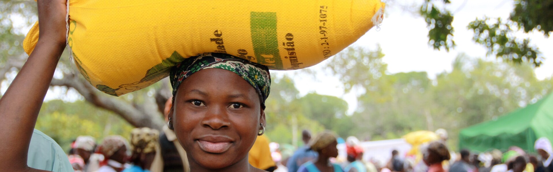 Eine Frau in Mosambik trägt einen Sack mit Lebensmitteln auf dem Kopf Eine Frau in Mosambik trägt einen Sack mit Lebensmitteln auf dem Kopf