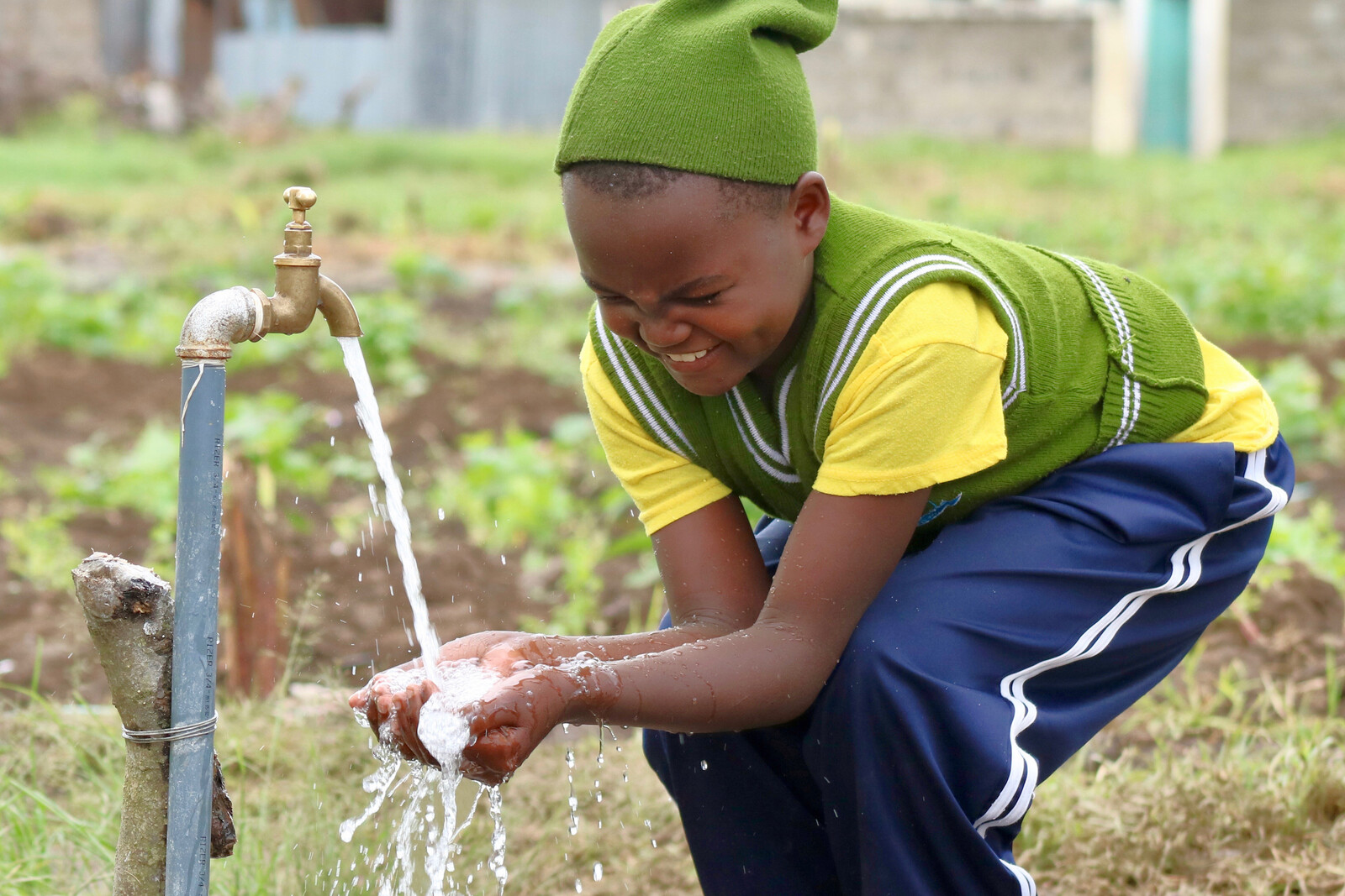 In Kenia freut sich ein Schulmädchen über das saubere Wasser, das aus dem Brunnen kommt