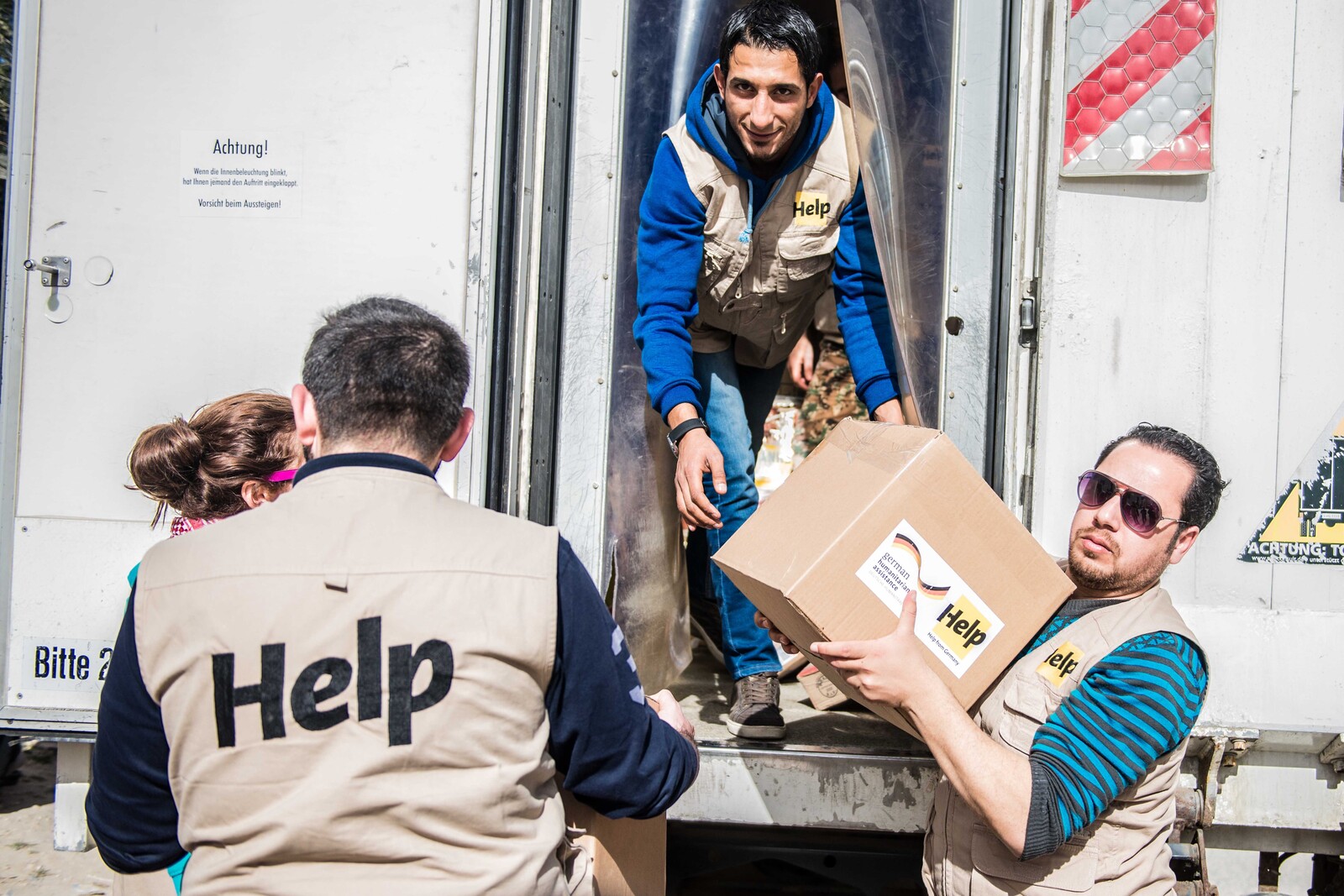 Mitarbeiter einer Hilfsorganisation entladen Versorgungspakete für syrische Flüchtlinge