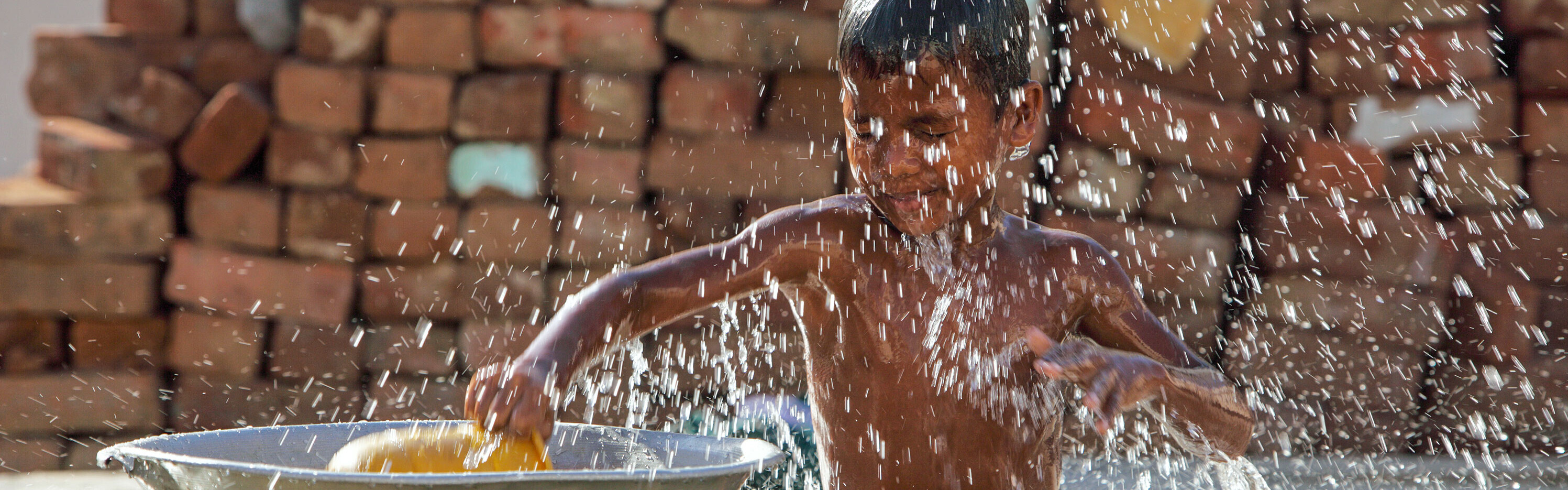 Ein Junge spielt mit Wasser.