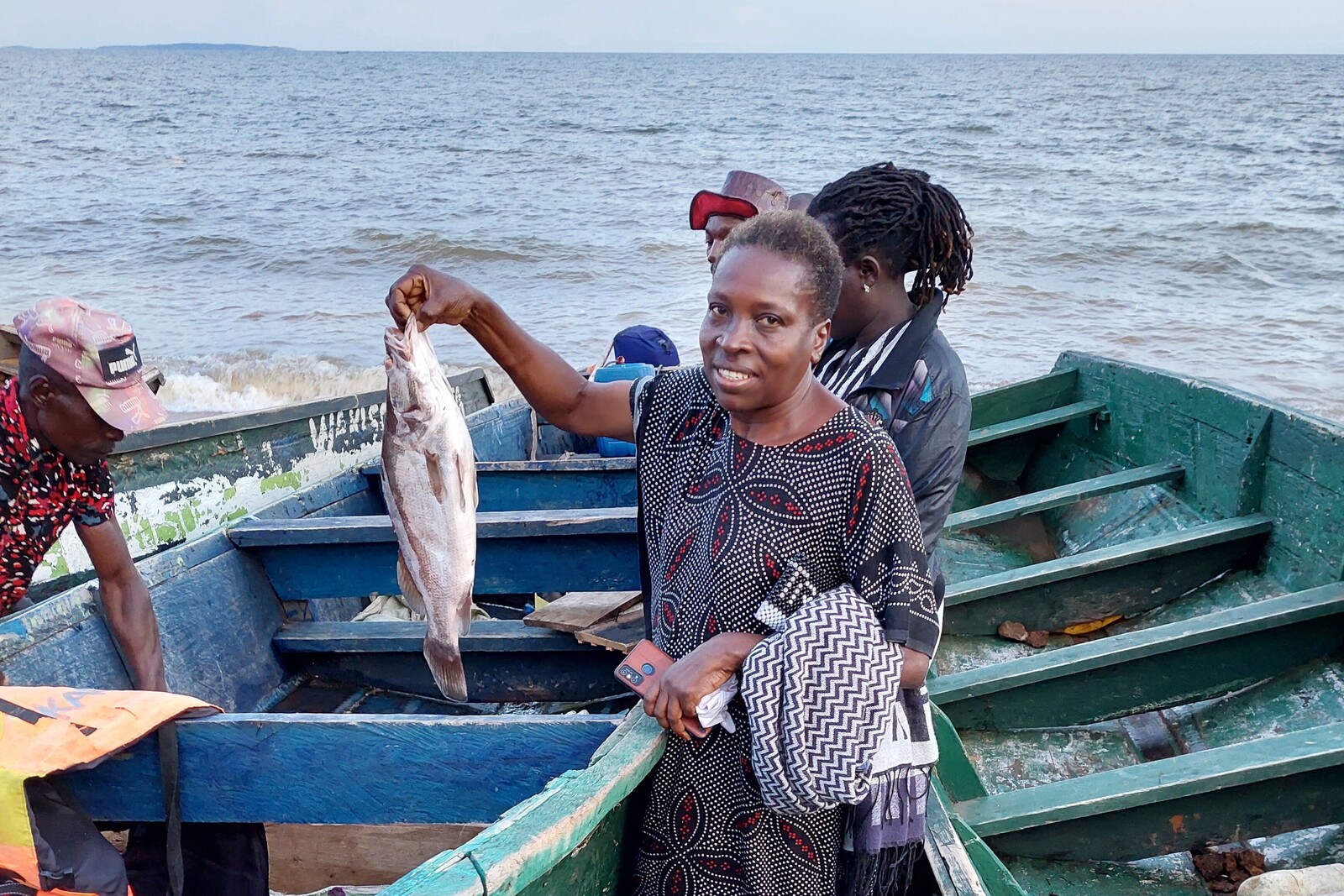 Eine Frau steht in einem Boot und hält einen Fisch