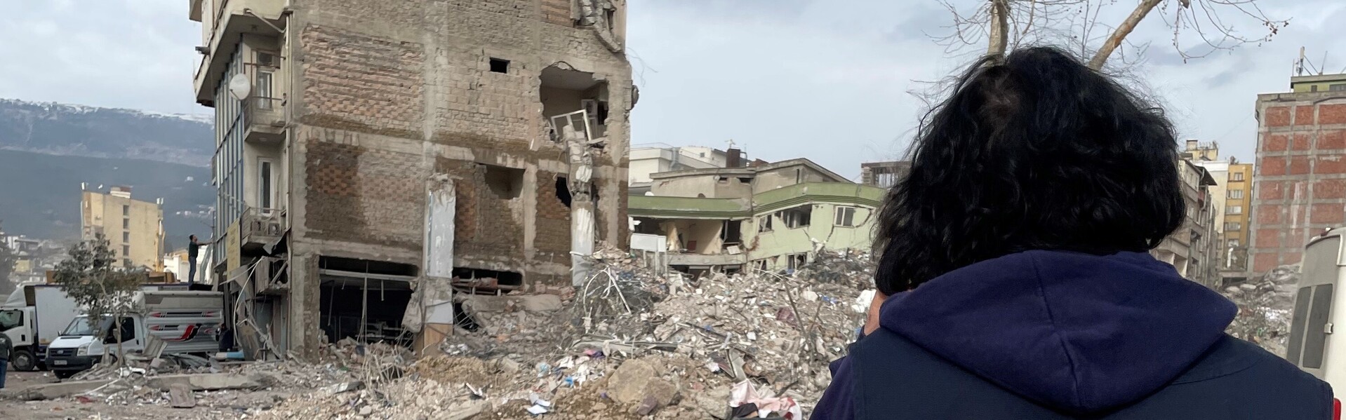 Eine Helferin von LandsAid blickt auf ein vom Erdbeben zerstörtes Haus Eine Helferin von LandsAid blickt auf ein vom Erdbeben zerstörtes Haus