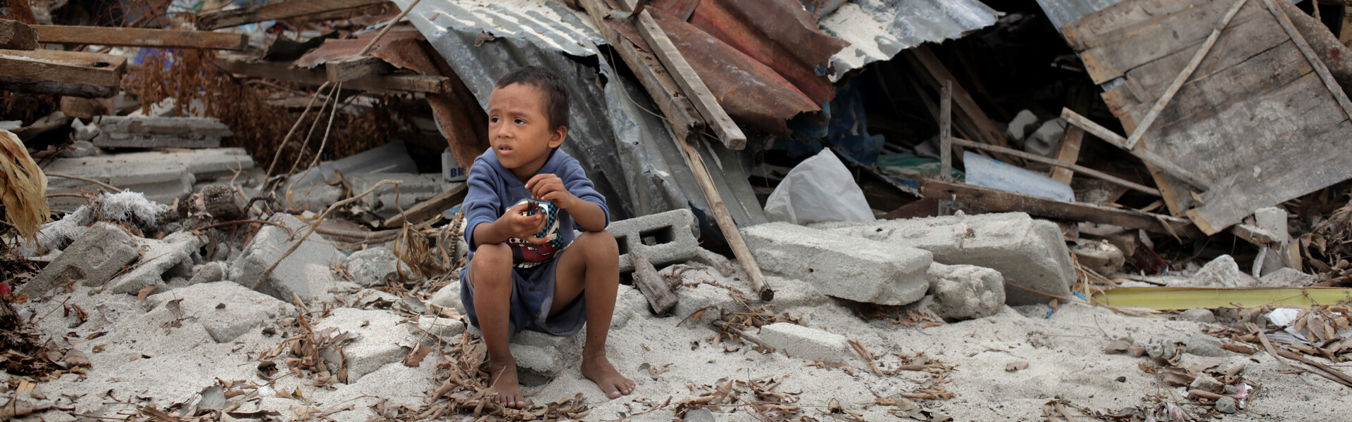 Kind sitzt vor einer Häuserruine auf den Philippinen nachdem Taifun Haiyan. Kind sitzt vor einer Häuserruine auf den Philippinen nachdem Taifun Haiyan.
