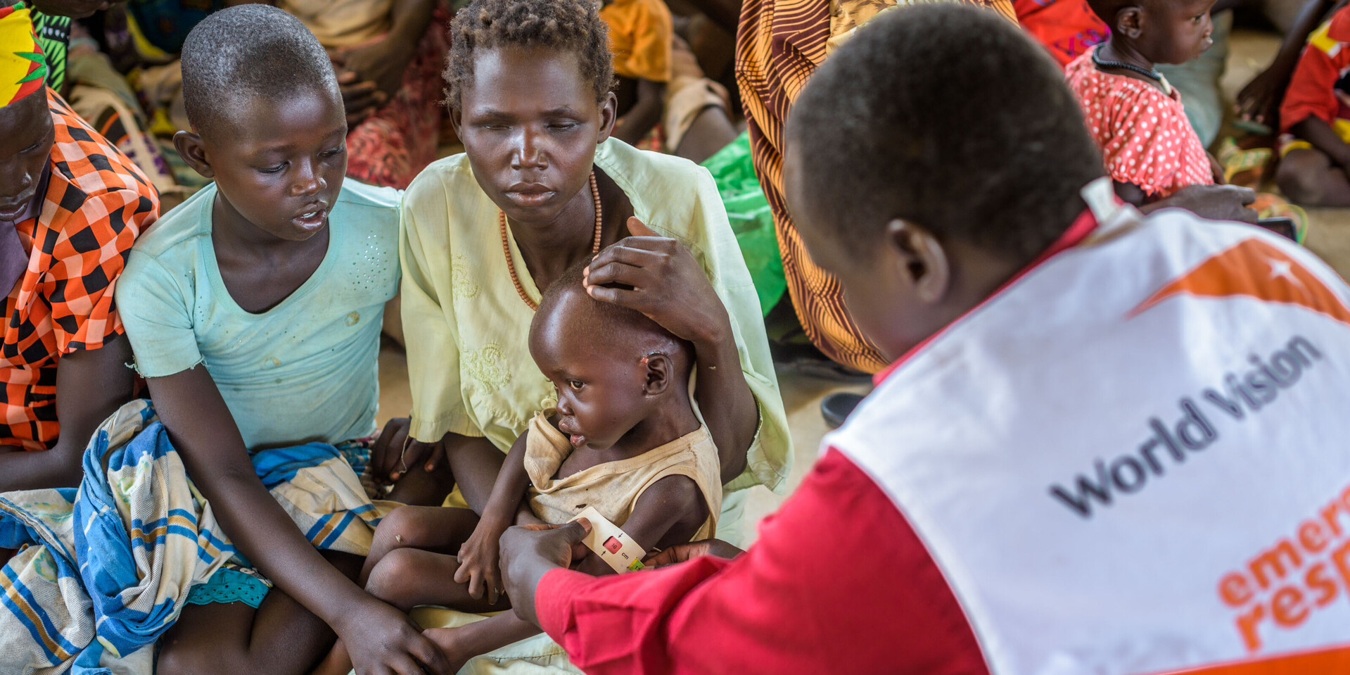Mit einem Hungermaßband misst ein Helfer den Oberarm eines Kleinkindes Mit einem Hungermaßband misst ein Helfer den Oberarm eines Kleinkindes