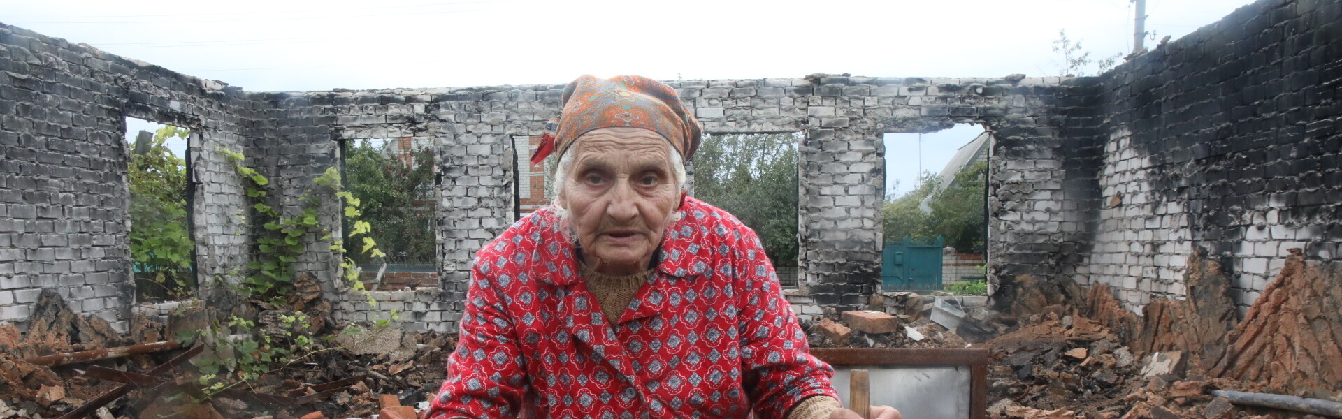 Eine alte Frau steht in der Ukraine in den Trümmern ihres Hauses Eine alte Frau steht in der Ukraine in den Trümmern ihres Hauses