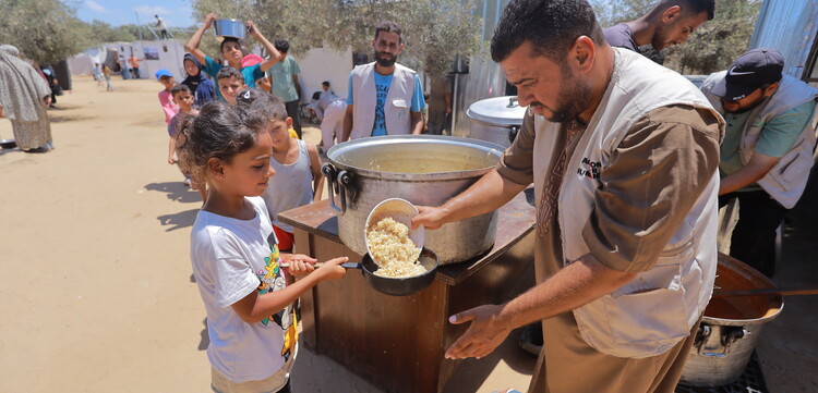 Ein Helfer verteilt Mahlzeiten an Kinder in Gaza