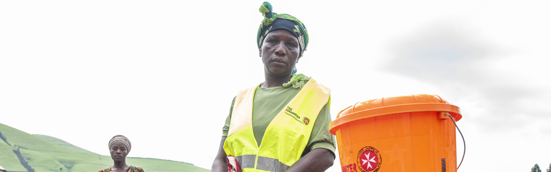 Eine Helferin der Johanniter vor einer Wasserstation in einem Camp für Geflüchtete Eine Helferin der Johanniter vor einer Wasserstation in einem Camp für Geflüchtete