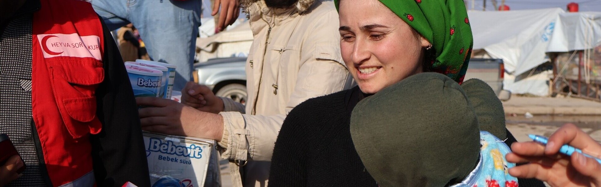 Eine syrische Frau erhält von einem Helfer Babynahrung und Spielzeug für ihr Kind Eine syrische Frau erhält von einem Helfer Babynahrung und Spielzeug für ihr Kind