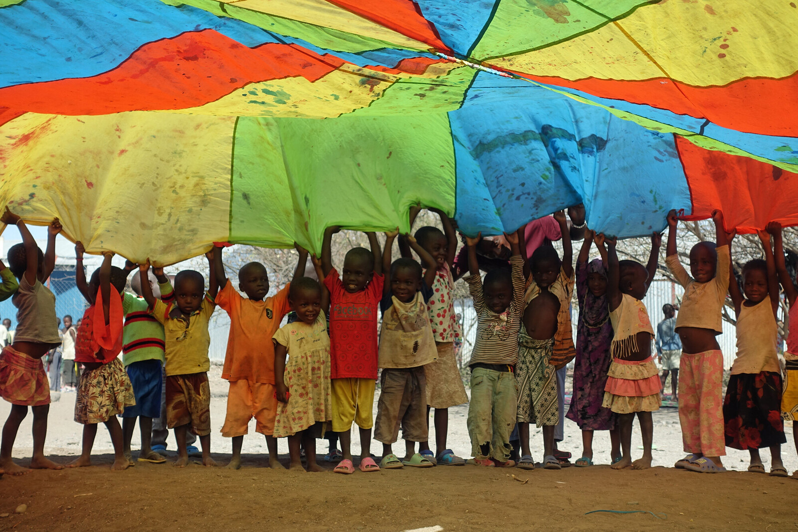 Kinder im Geflüchtetencamp Kakuma spielen mit einem bunten Schwungtuch