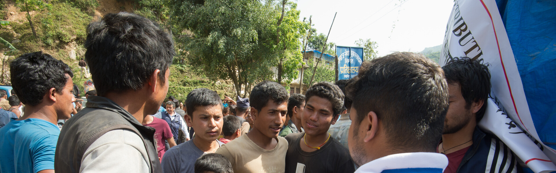 Ein Helfer von AWO International steht in einer Menschenmenge und ein Kind hält den Daumen hoch.