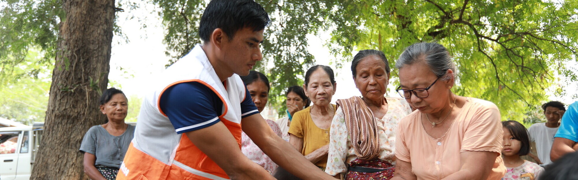Ein Helfer von World Vision überreicht einer Gruppe Frauen in Myanmar eine Hilfslieferung Ein Helfer von World Vision überreicht einer Gruppe Frauen in Myanmar eine Hilfslieferung