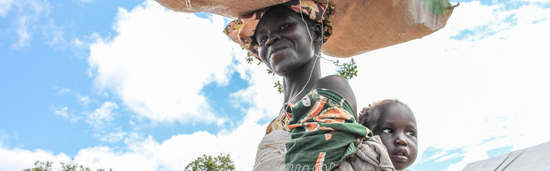Frauen in Uganda haben kaum Zugang zu sauberen und preiswerten Menstruationsartikeln Eine Frau in Uganda trägt ihr Baby in einem Tuch auf dem Rücken