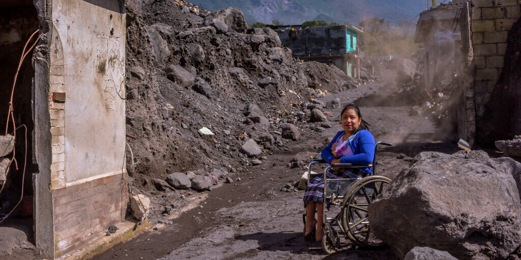Eine Frau in Guatemala sitzt im Rollstuhl, umgeben von Trümmern Eine Frau in Guatemala sitzt im Rollstuhl, umgeben von Trümmern