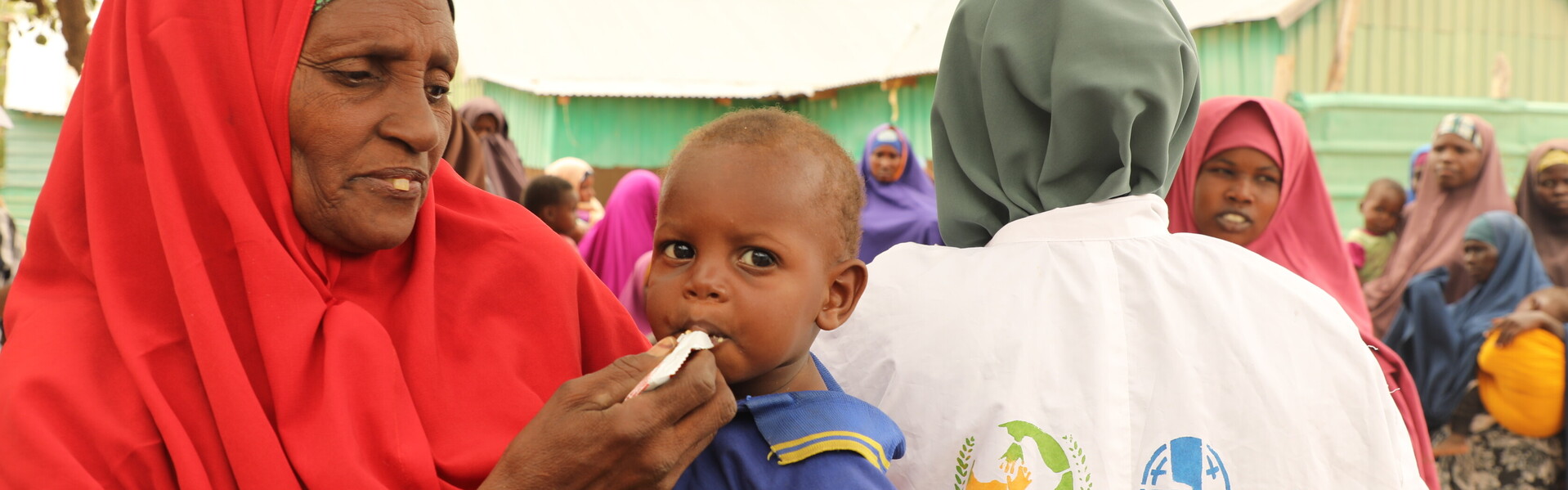 Helfer einer Hilfsorganisation unterstützt Frauen und Kinder mit Notfallnahrung Helfer einer Hilfsorganisation unterstützt Frauen und Kinder mit Notfallnahrung