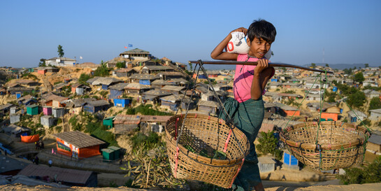 Ein Kind in Bangladesch trägt zwei Körbe Ein Kind in Bangladesch trägt zwei Körbe