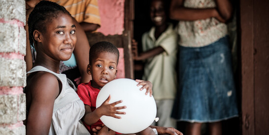 Eine Frau hat in Haiti einen Jungen auf ihrem Schoß sitzen Eine Frau hat in Haiti einen Jungen auf ihrem Schoß sitzen