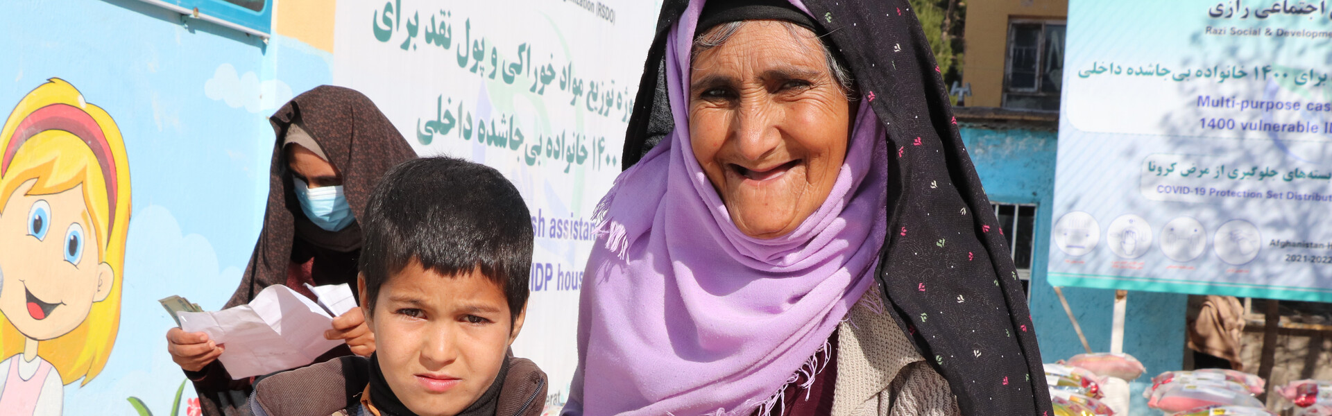 Eine Frau steht neben einem Jungen bei einer Lebensmittelverteilung in Afghanistan Eine Frau steht neben einem Jungen bei einer Lebensmittelverteilung in Afghanistan