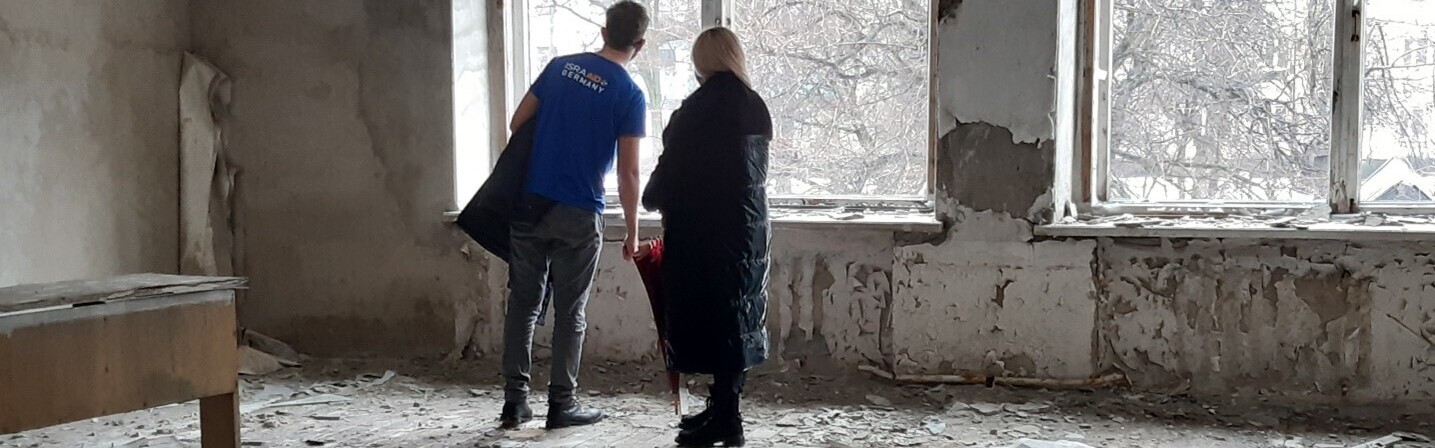 Ukraine Krieg: Ein Mann und eine Frau stehen in einem zerstörten Haus Ukraine Krieg: Ein Mann und eine Frau stehen in einem zerstörten Haus