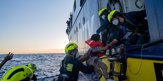 Geflüchtete werden auf Rettungsboot gezogen Geflüchtete werden auf Rettungsboot gezogen