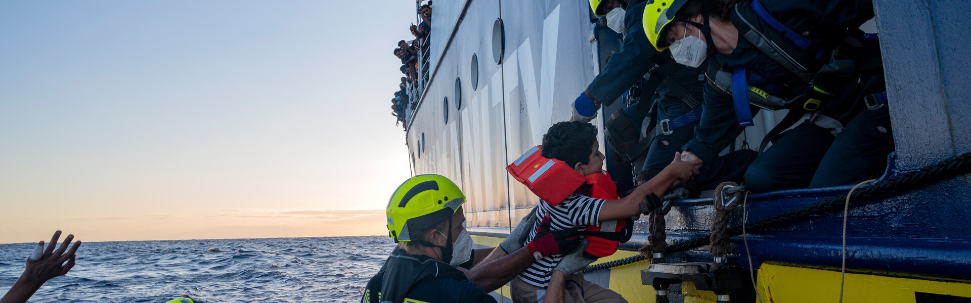 Geflüchtete werden auf Rettungsboot gezogen Geflüchtete werden auf Rettungsboot gezogen
