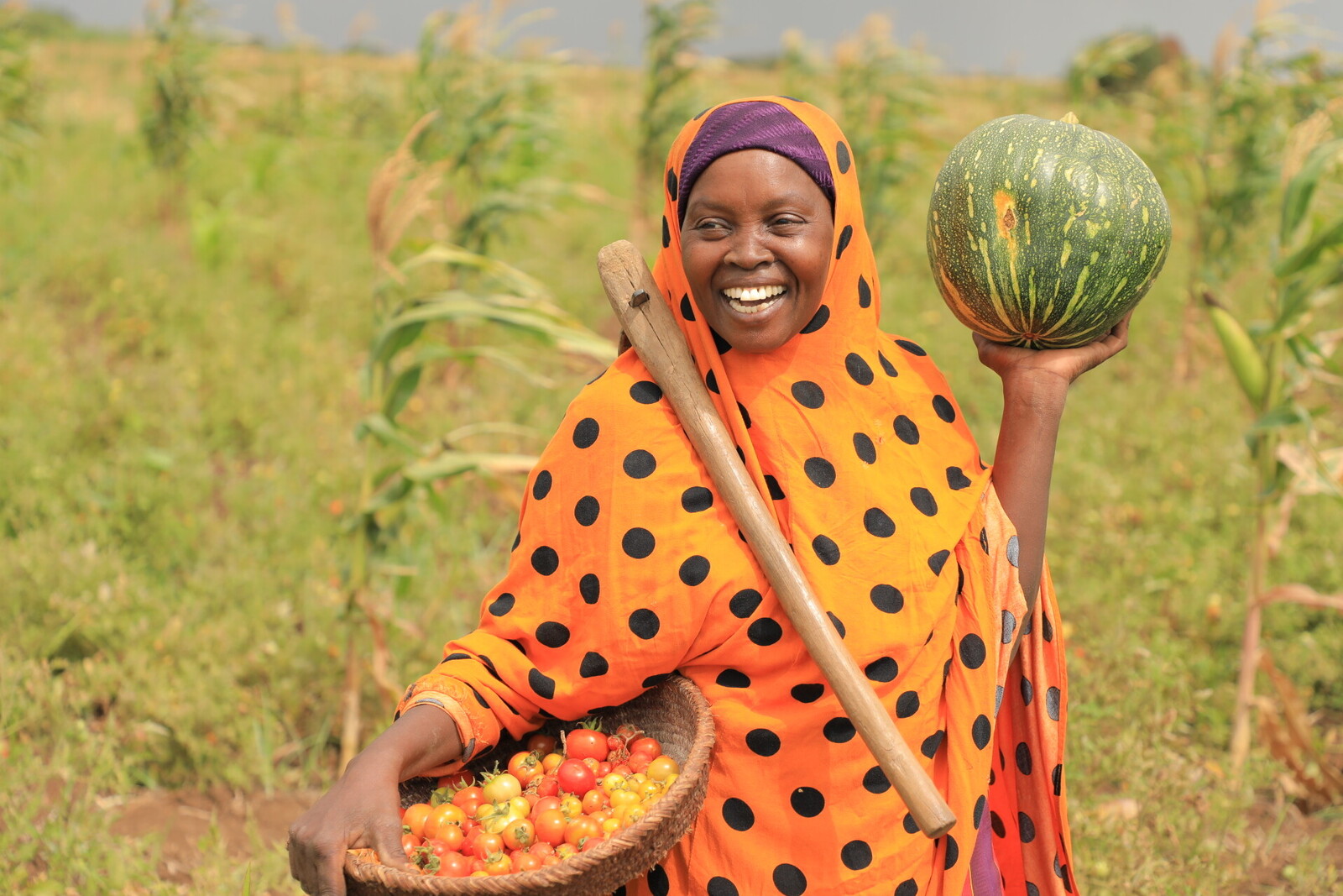 Eine Frau steht in Somalia mit frisch geerntetem Obst und Gemüse auf dem Feld