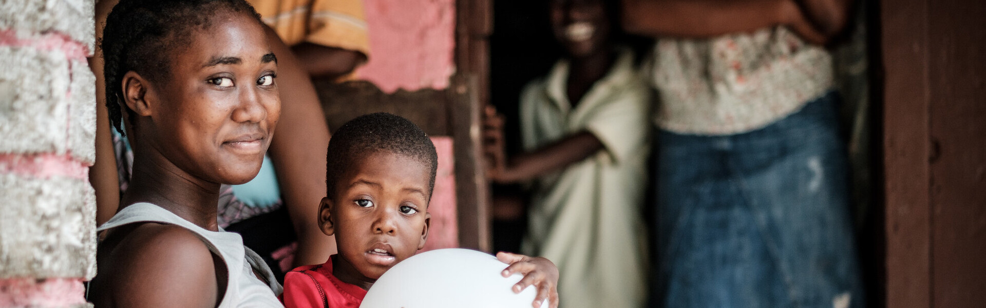 Eine Frau hat in Haiti einen Jungen auf ihrem Schoß sitzen Eine Frau hat in Haiti einen Jungen auf ihrem Schoß sitzen