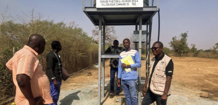 Fünf Männer stehen vor einer neu gebauten Brunnenanlage in Burkina Faso