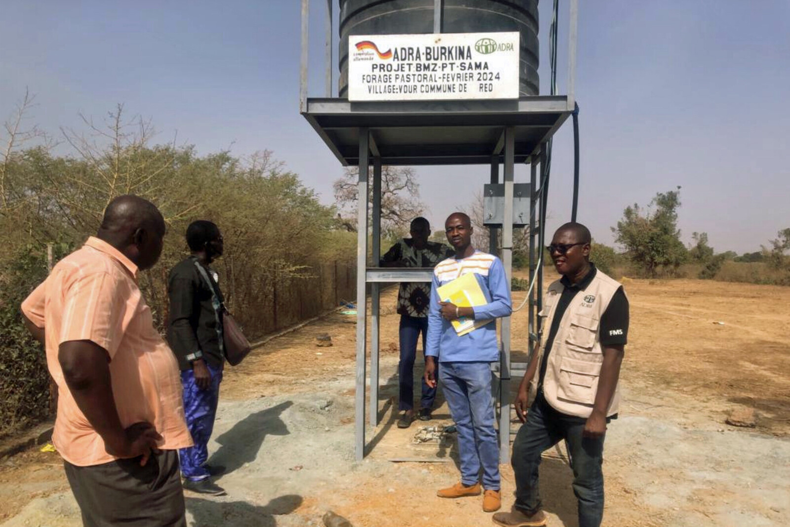 Fünf Männer stehen vor einer neu gebauten Brunnenanlage in Burkina Faso