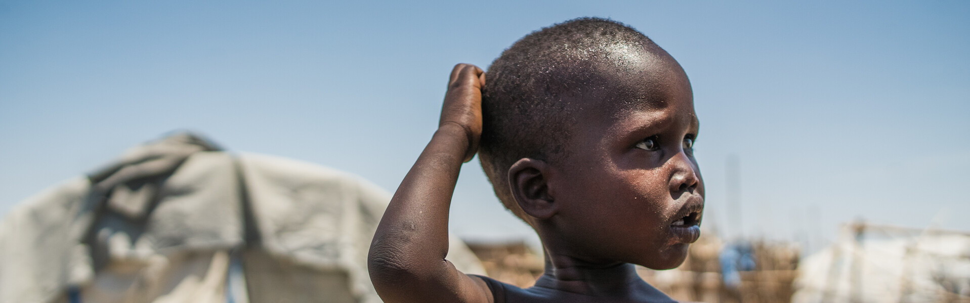 Ein Junge im Südsudan steht vor einem Flüchtlingszelt. Ein Junge im Südsudan steht vor einem Flüchtlingszelt.
