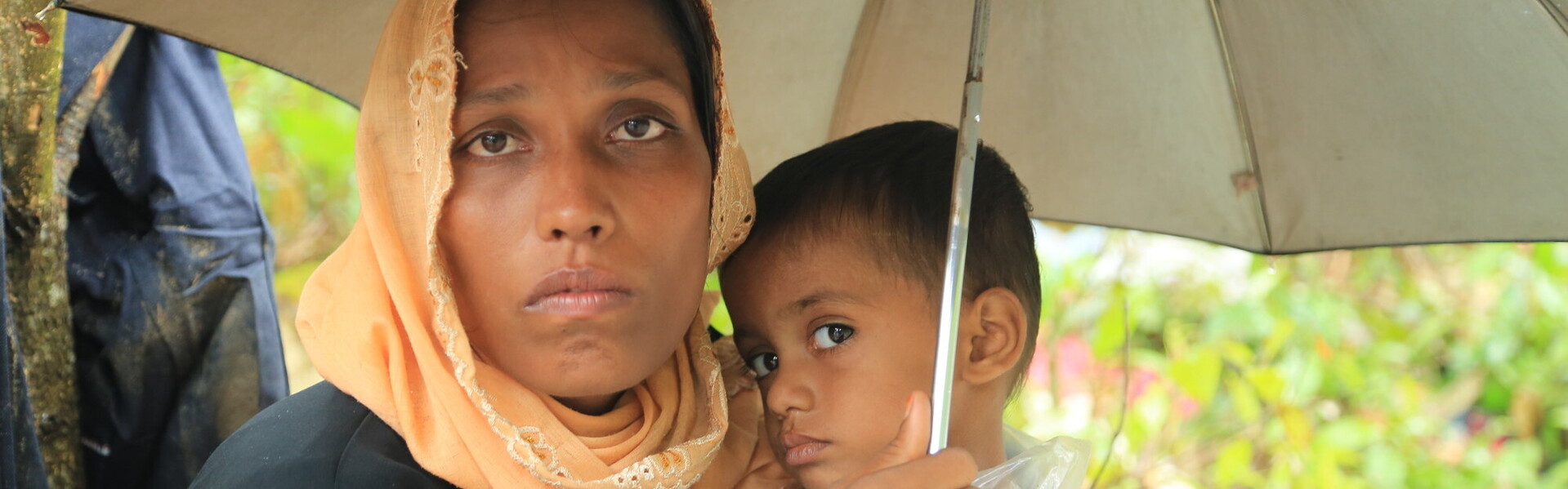 Frau & Kind schützen sich mit einem Schirm vor Monsunregen Frau & Kind schützen sich mit einem Schirm vor Monsunregen