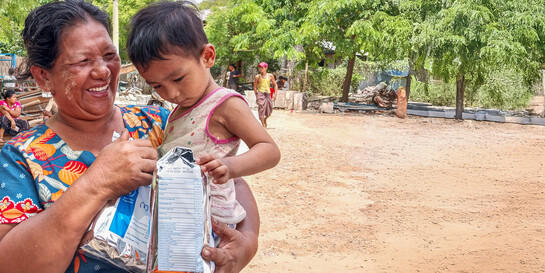 Eine Frau mit Kind auf dem Arm erhält von World Vision nach dem Erdbeben in Myanmar Lebensmittelpakete Eine Frau mit Kind auf dem Arm erhält von World Vision nach dem Erdbeben in Myanmar Lebensmittelpakete