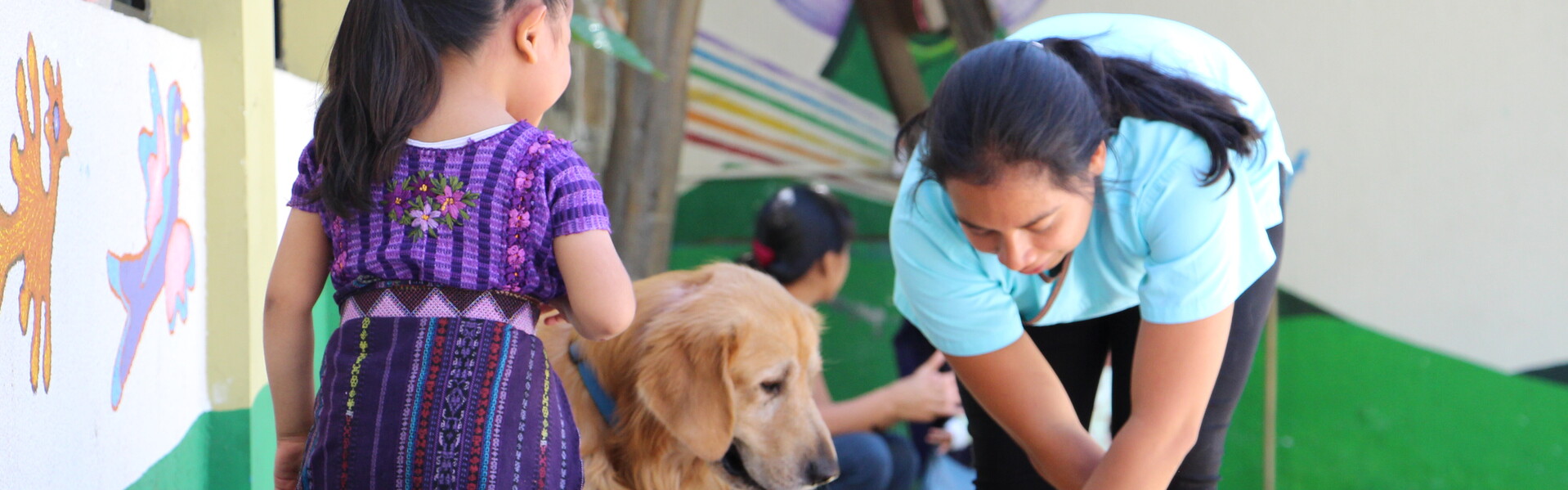 Frau stellt einem Kind mit Behinderung Hütchen hin in Guatemala. Frau stellt einem Kind mit Behinderung Hütchen hin in Guatemala.