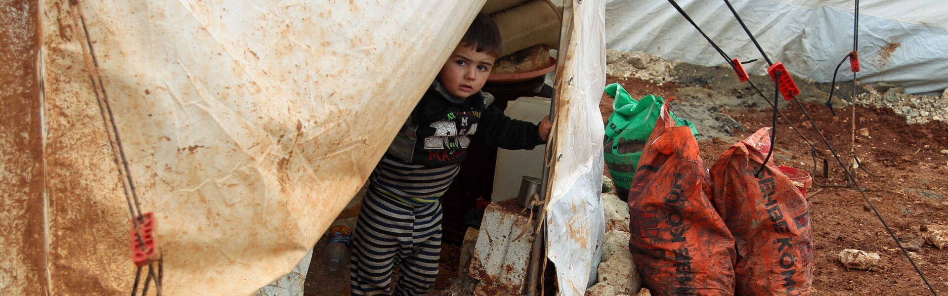 Ein kleiner Junge in einer notdürftigen Unterkunft für Flüchtlinge Ein kleiner Junge in einer notdürftigen Unterkunft für Flüchtlinge