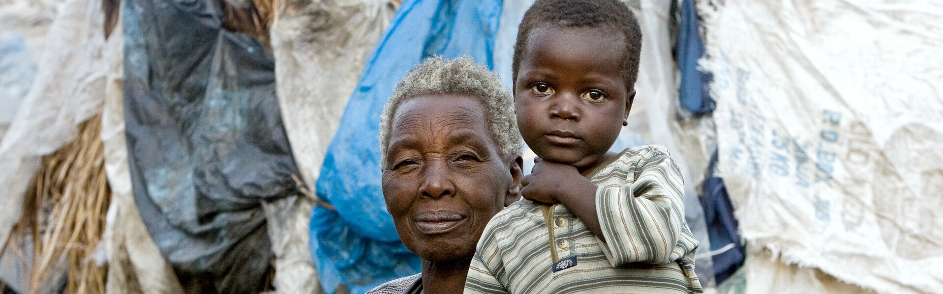 In der Demokratischen Republik Kongo herrscht eine unsichere Lage. Viele Menschen fliehen vor Gewalt und Krieg. Eine Oma sitzt mit ihrem Enkel in einem Flüchtlingslager. In der Demokratischen Republik Kongo herrscht eine unsichere Lage. Viele Menschen fliehen vor Gewalt und Krieg. Eine Oma sitzt mit ihrem Enkel in einem Flüchtlingslager.