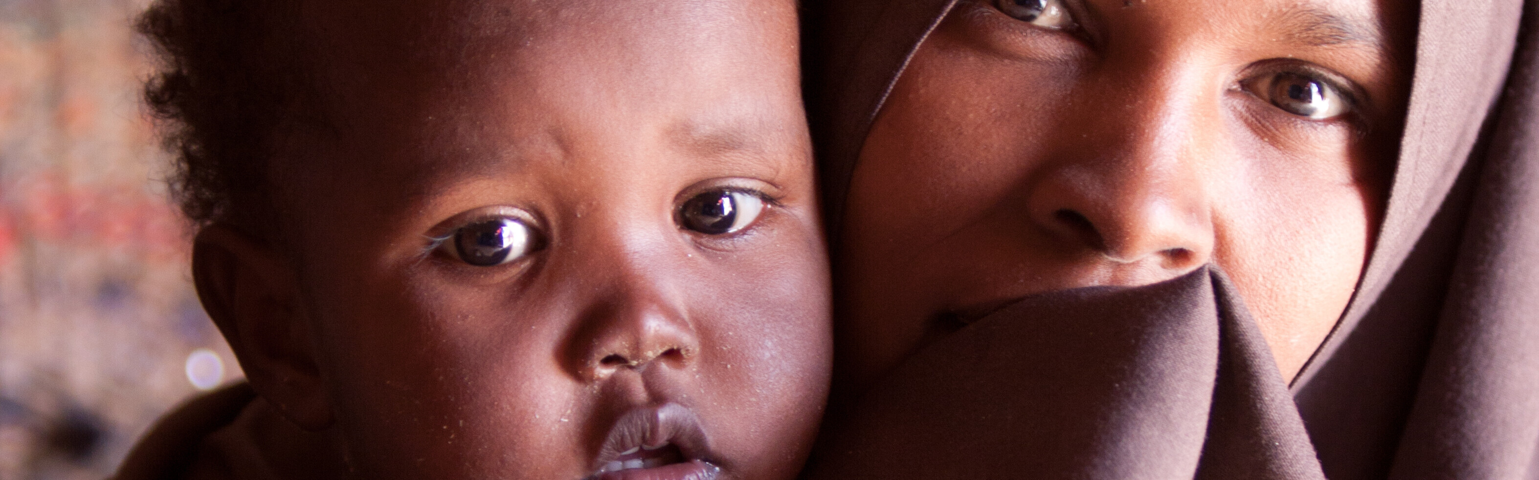 In Afrika herrscht oft Dürre und Hunger. Eine Frau mit ihrem Kind auf dem Arm sitzt in einem Zelt.