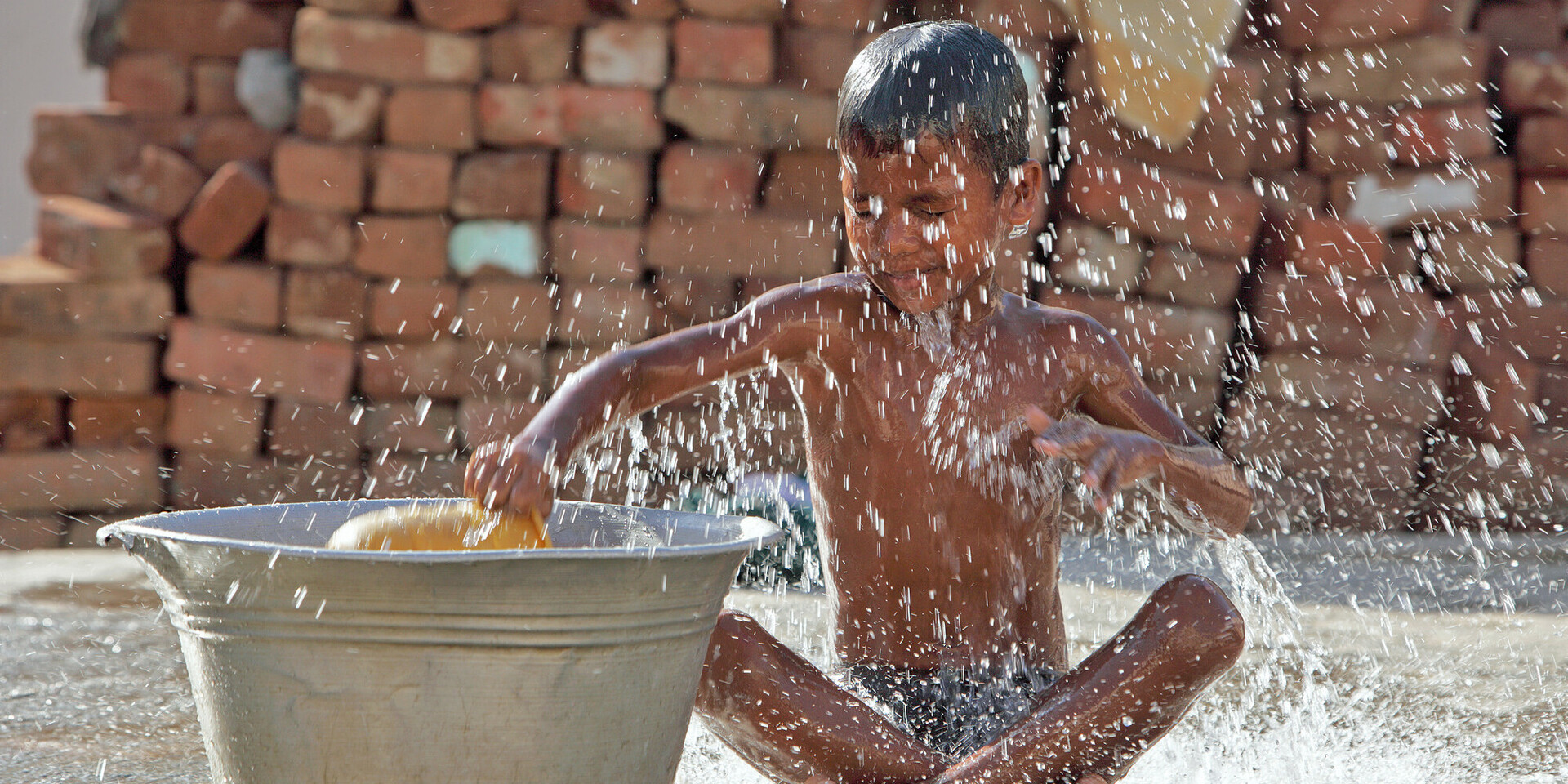 Ein Kind spielt mit einem Wasserbehälter Ein Kind spielt mit einem Wasserbehälter