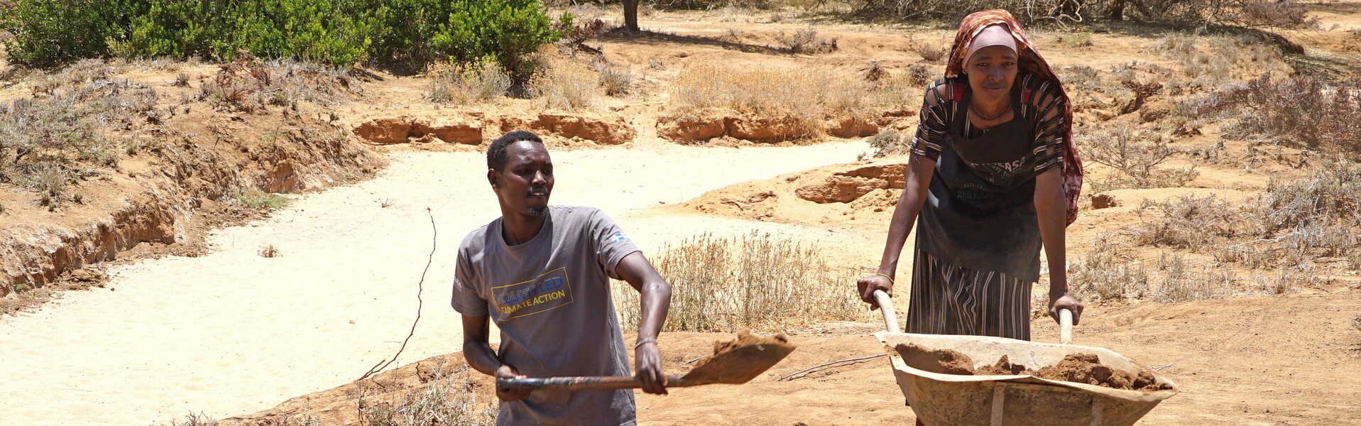Ein Mann und eine Frau in Afrika bewirtschaften einen trockenen Ackerboden Ein Mann und eine Frau in Afrika bewirtschaften einen trockenen Ackerboden