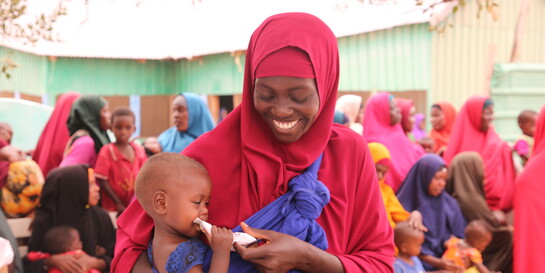 Frau mit Kind, das Notfallnahrung gegen Hunger erhalten hat, in Somalia Themenseite Hungersnot