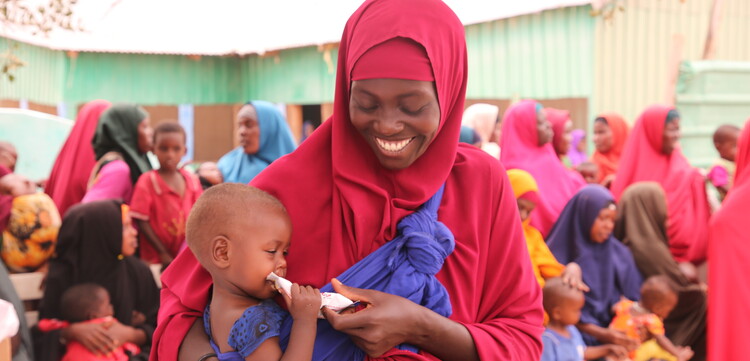 Frau mit Kind, das Notfallnahrung gegen Hunger erhalten hat, in Somalia