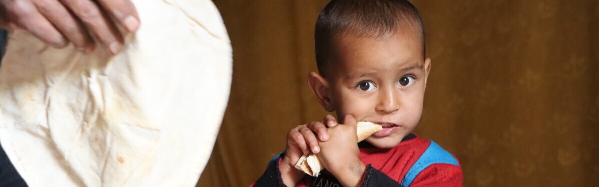 Ein kleiner Junge kaut auf einem Fladenbrot Ein kleiner Junge kaut auf einem Fladenbrot