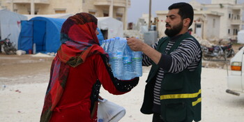 Helfer verteilt Trinkwasser im Erdbebengebiet Helfer verteilt Trinkwasser im Erdbebengebiet