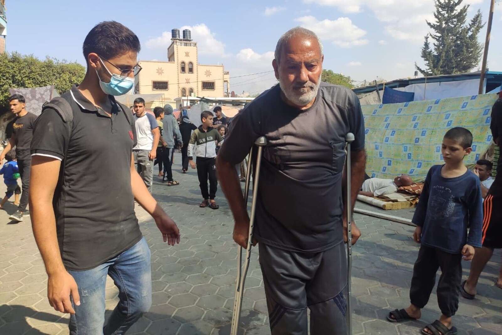 Ein Helfer in Gaza mit einem Mann, der Gehhilfen benötigt