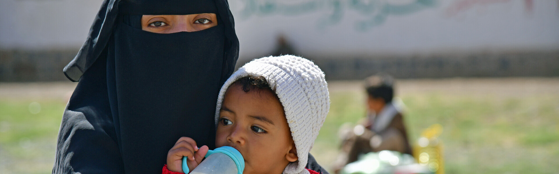 Fast 19 Millionen Menschen im Jemen sind von Hunger bedroht, vor allem Kinder Eine Frau mit schwarzem Nikab trägt ein Baby mit Milchflasche