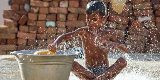 Ein Junge spielt mit Wasser.