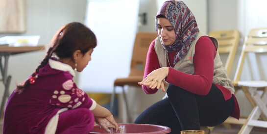 Eine Helferin zeigt einem Mädchen das richtige Händewaschen Eine Helferin zeigt einem Mädchen das richtige Händewaschen