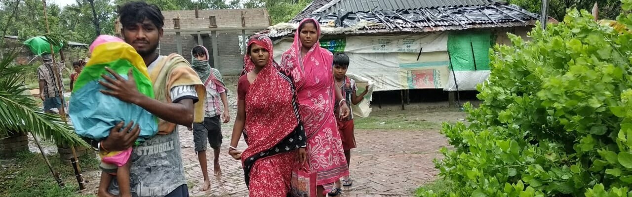 Eine Familie in Bangladesch rettet sich nach dem Zyklon Amphan in eine sichere, trockene Unterkunft Eine Familie in Bangladesch rettet sich nach dem Zyklon Amphan in eine sichere, trockene Unterkunft