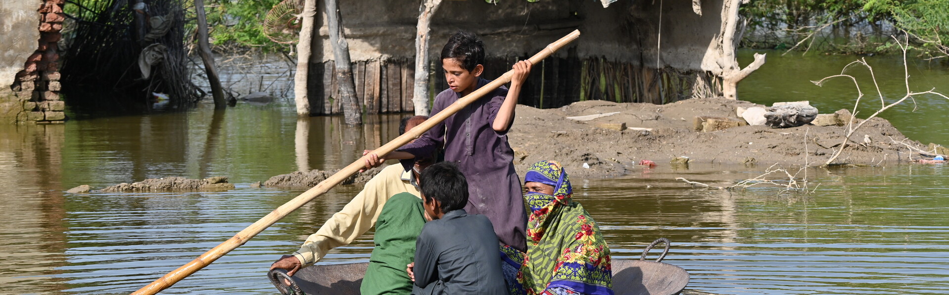 In einer großen Metallpfanne rettet sich eine Familie vor den Überschwemmungen in Pakistan In einer großen Metallpfanne rettet sich eine Familie vor den Überschwemmungen in Pakistan