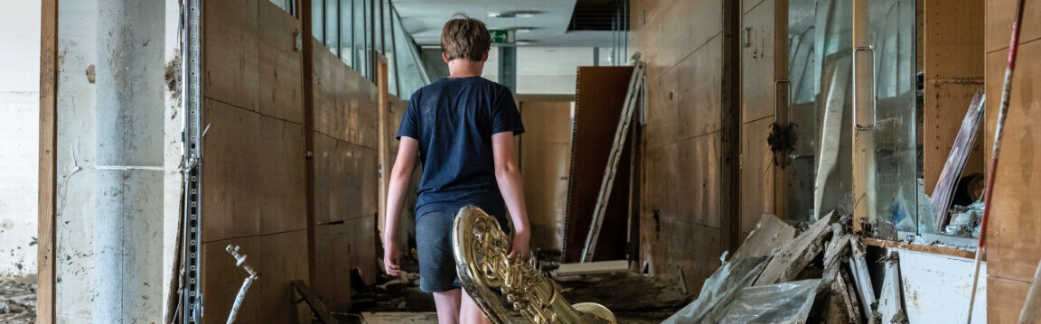 Eine Junge trägt seine Posaune durch das von den Fluten stark betroffene Peter-Joerres-Gymnasium in Ahrweiler Eine Junge trägt seine Posaune durch das von den Fluten stark betroffene Peter-Joerres-Gymnasium in Ahrweiler